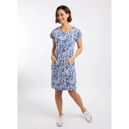 A woman wearing a Weird Fish short sleeve Tallahassee dress in Sapphire Blue featuring an abstract floral print with front pockets and white trainers.