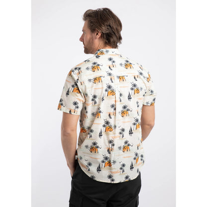 Back view of a man wearing a Weird Fish short sleeve Faraway shirt in Ecru with a tropical island, palm trees, sun and sailboat pattern