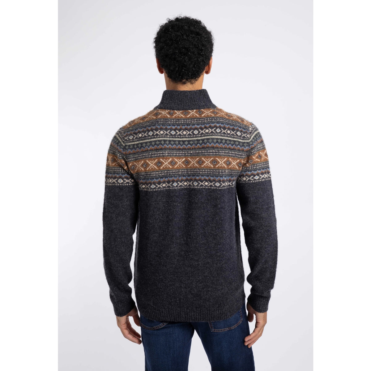 Back view of a man wearing a Weird Fish 1/4 zip Larner knitted jumper in Midnight Navy with a Fair Isle pattern across the chest and shoulders with blue jeans.