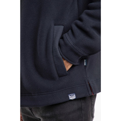Close up of a dark navy mens Weird Fish Boyd fleece jacket pocket with a visible brand logo on a white background