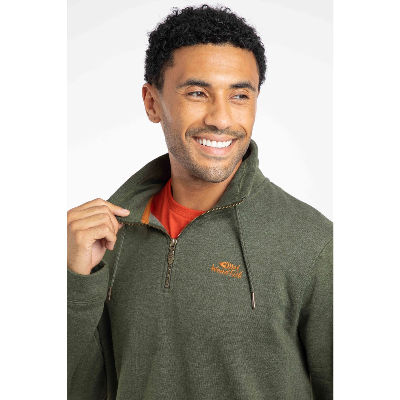 Man wearing a Weird Fish green Brampton 1/4 zip sweatshirt with a logo on a white background