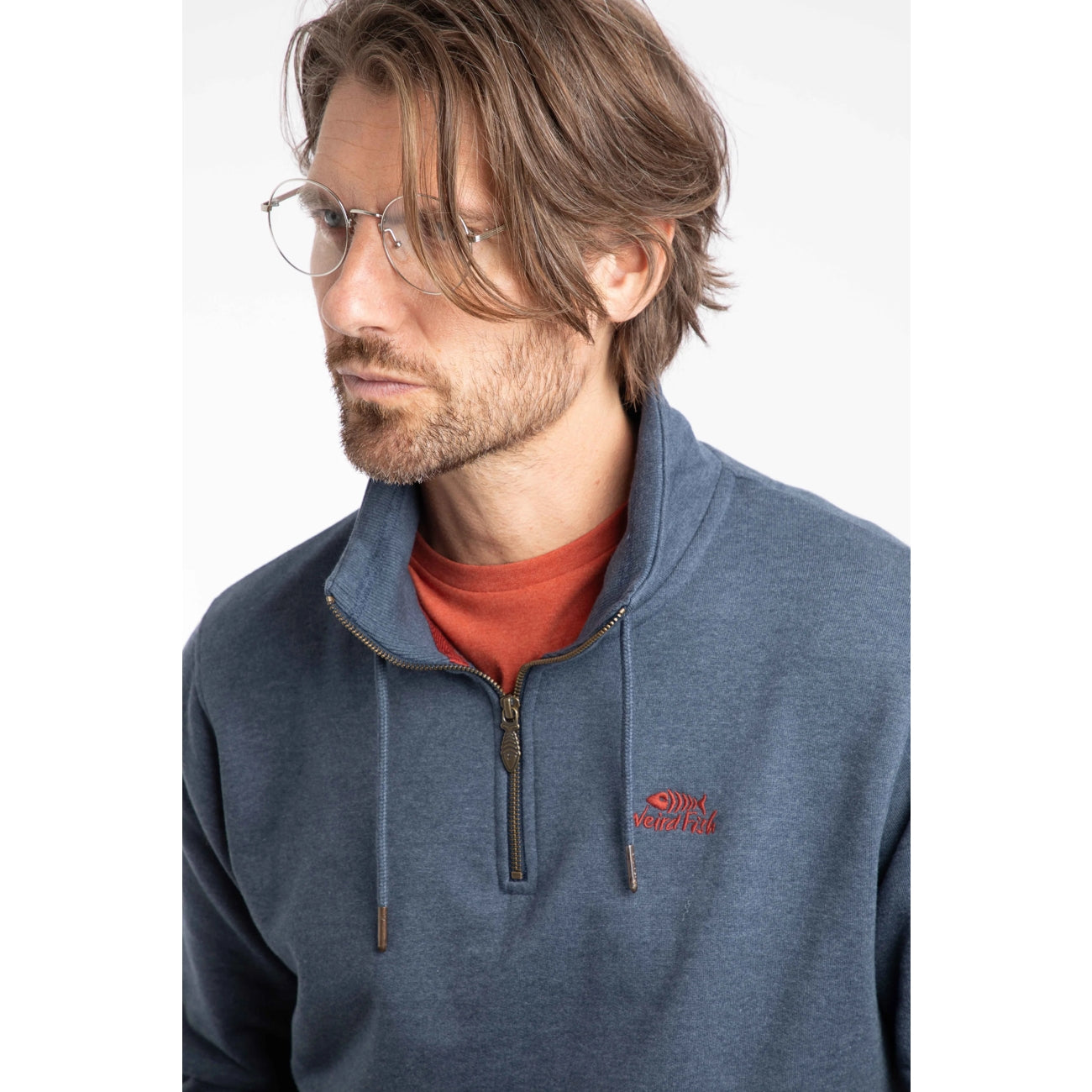 Man wearing a Weird Fish navy blue Brampton pullover sweatshirt with a red logo on a white background