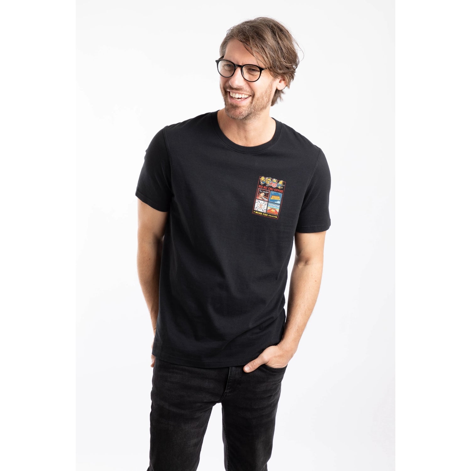 Front view of a man wearing a Weird Fish mens short sleeve Chili Kippers t-shirt in black with a small Red Hot Chili Kippers album themed print on the front