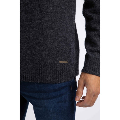 Close-up view of the logo fob on a men's Weird Fish 1/4 zip Larner knitted jumper in Midnight Navy with a Fair Isle pattern across the chest and shoulders with blue jeans.