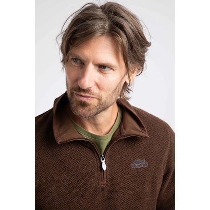 Close-up view of a man wearing a Weird Fish quarter zip textured Errill fleece in Chocolate brown with a small logo on one side of the chest.