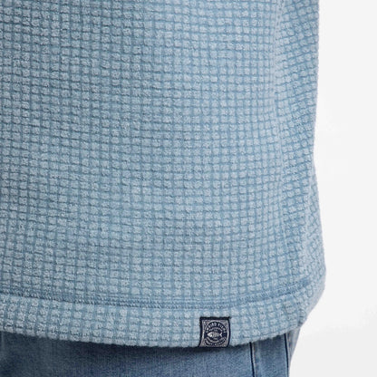 Close-up view of a logo label on the hem of a mens Weird Fish Newark grid fleece in light blue