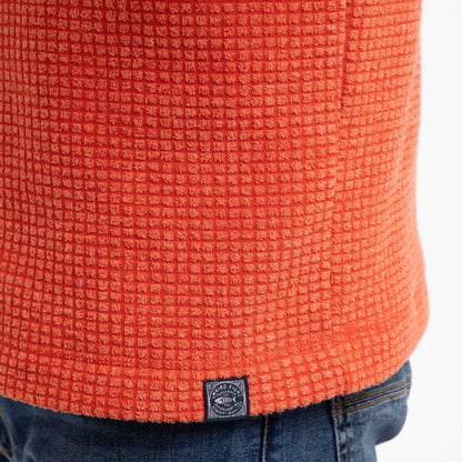 Close-up view of a logo label on the hem of a mens Weird Fish Newark grid fleece in Orange Spice