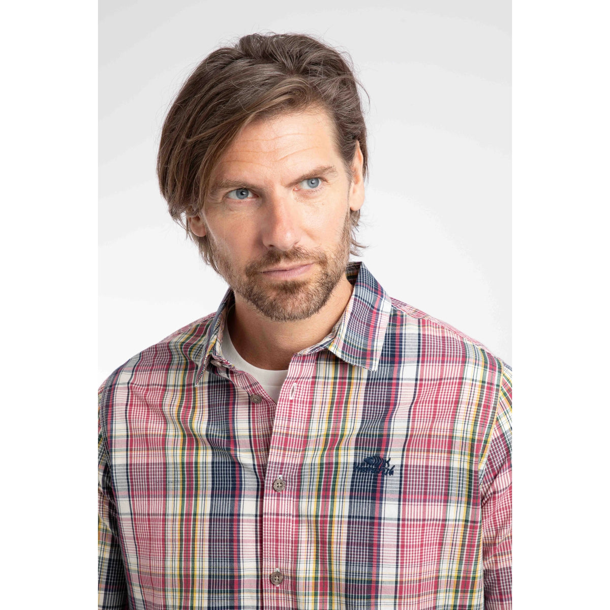 Close-up view of a man wearing a Weird Fish long sleeve Lando shirt, in a crushed berry, navy, yellow and white check pattern.