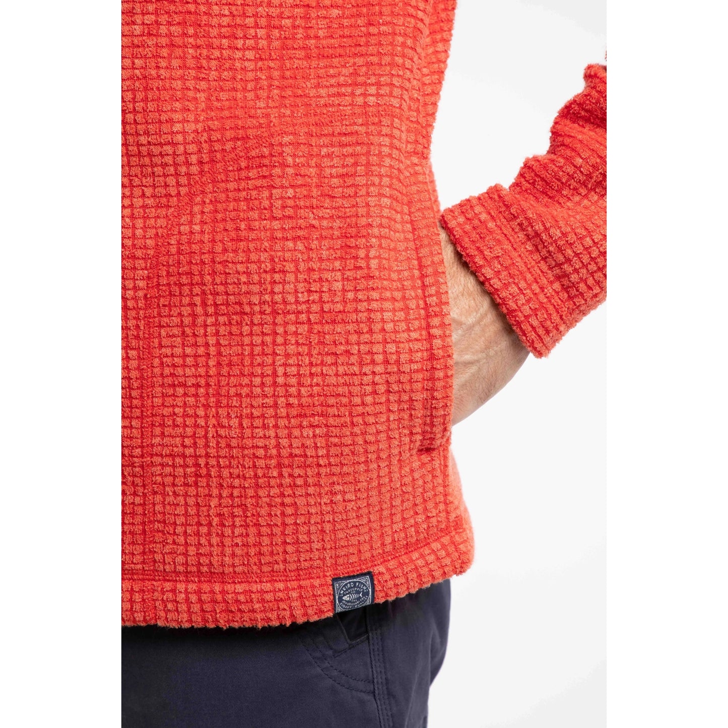 Close-up view of a tummy pocket on a mens Weird Fish full zip Shires grid textured fleece in bright Orange Spice 