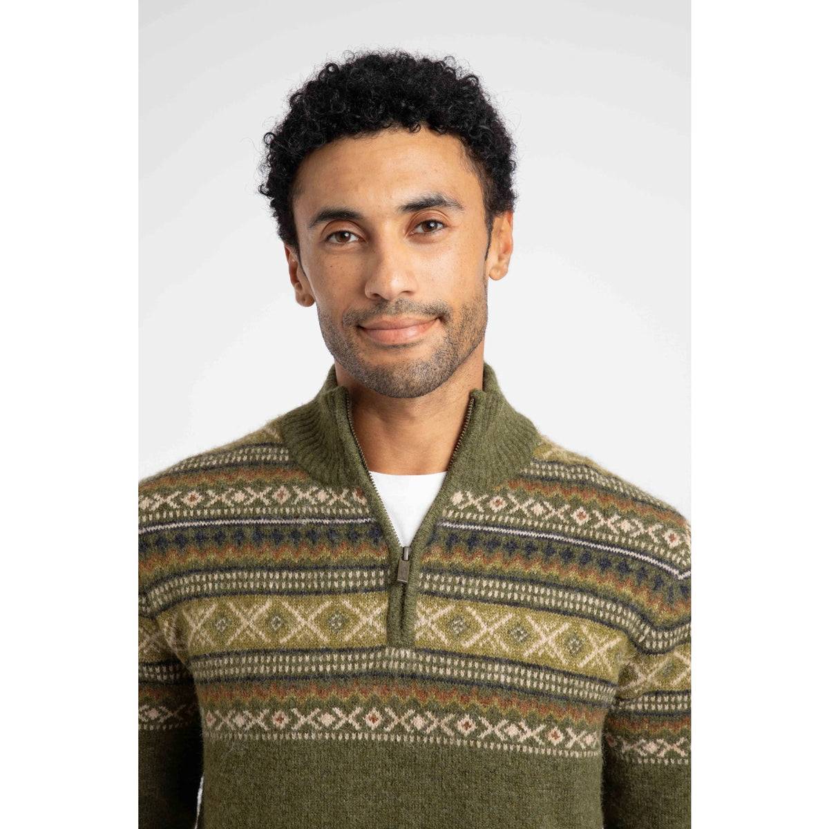 Close-up view of a man wearing a Weird Fish 1/4 zip Larner knitted jumper in Winter Green with a Fair Isle pattern across the chest and shoulders.
