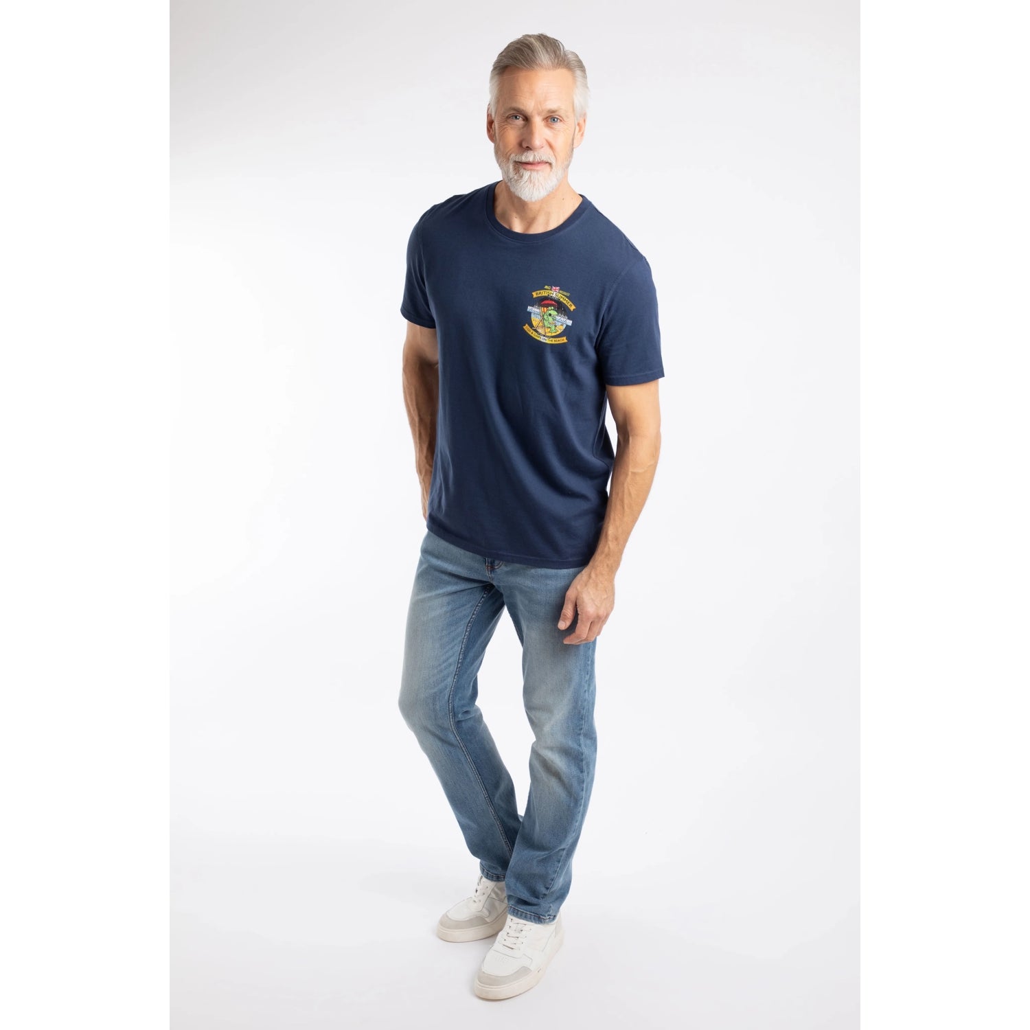 A man wearing a Weird Fish Cod and Chips print short sleeve t-shirt in Dark Blue with blue jeans and white shoes