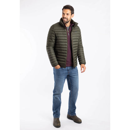 A man wearing a Weird Fish Crantock padded showerproof jacket in Anthracite  with blue jeans and brown boots
