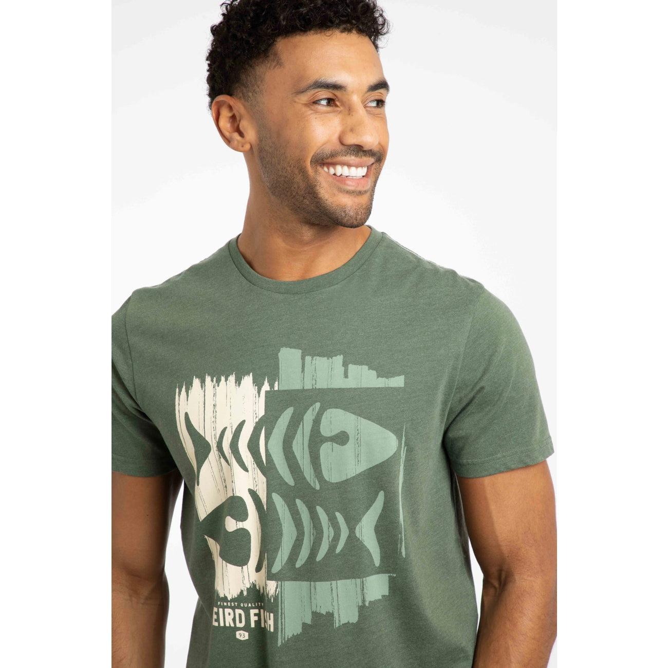 Closeup of a man wearing a Weird Fish short sleeve tee in Deep Lichen Green with a distressed style fishbones print on the front on a white background