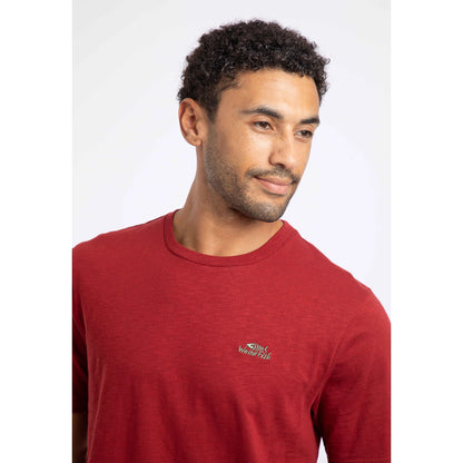 Close-up view of a man wearing a Weird Fish crew neck short sleeve Fished t-shirt in Barn Red with small logo on one side of the chest.
