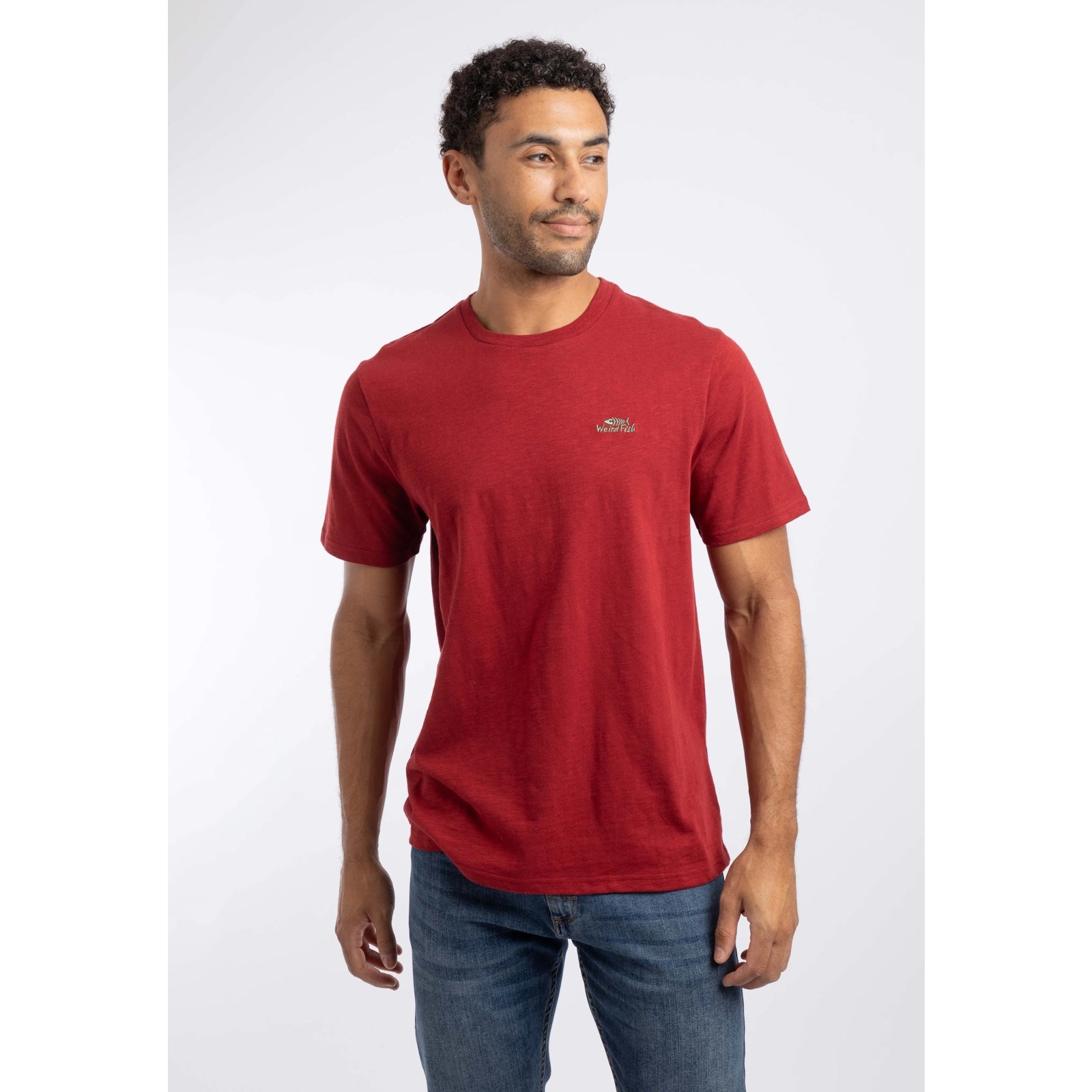 Front view of a man wearing a Weird Fish crew neck short sleeve Fished t-shirt in Barn Red with small logo on one side of the chest.