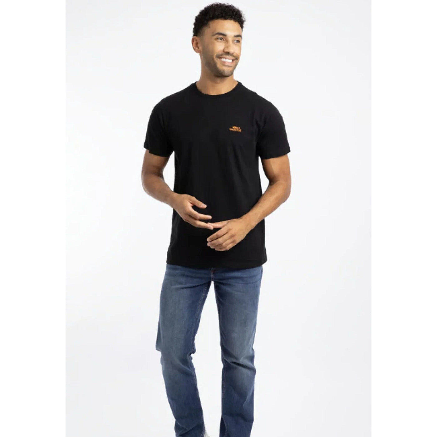 A man wearing a Weird Fish short sleeve Fished t-shirt in black with a small orange logo on the chest with blue jeans.