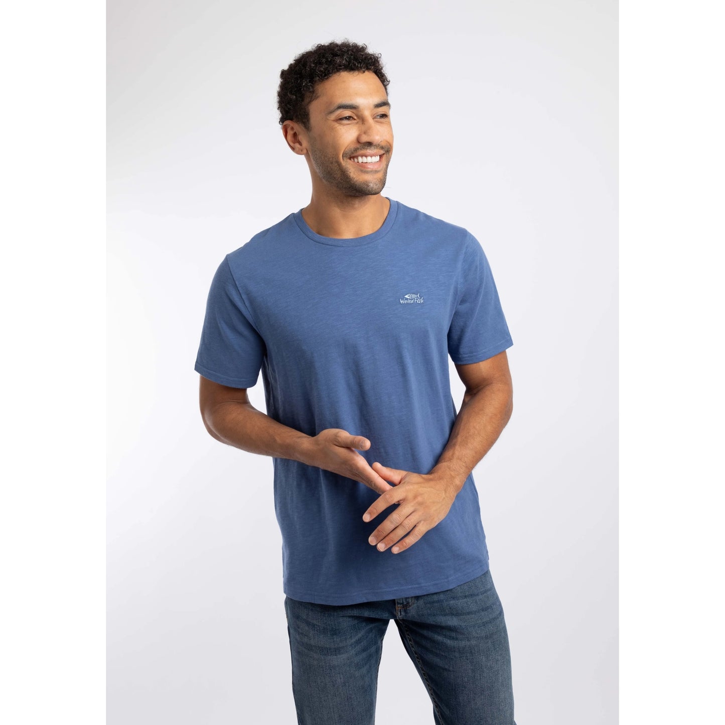 Front view of a man wearing a Weird Fish short sleeve Fished t-shirt in Faded Blue with a small logo on the chest.