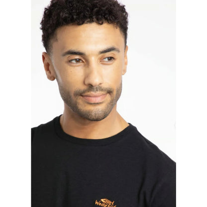 Close-up view of a man wearing a Weird Fish short sleeve Fished t-shirt in black with a small orange logo on the chest.