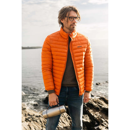 A man wearing a Weird Fish Crantock padded lightweight showerproof jacket in bright Koi Orange outdoor.