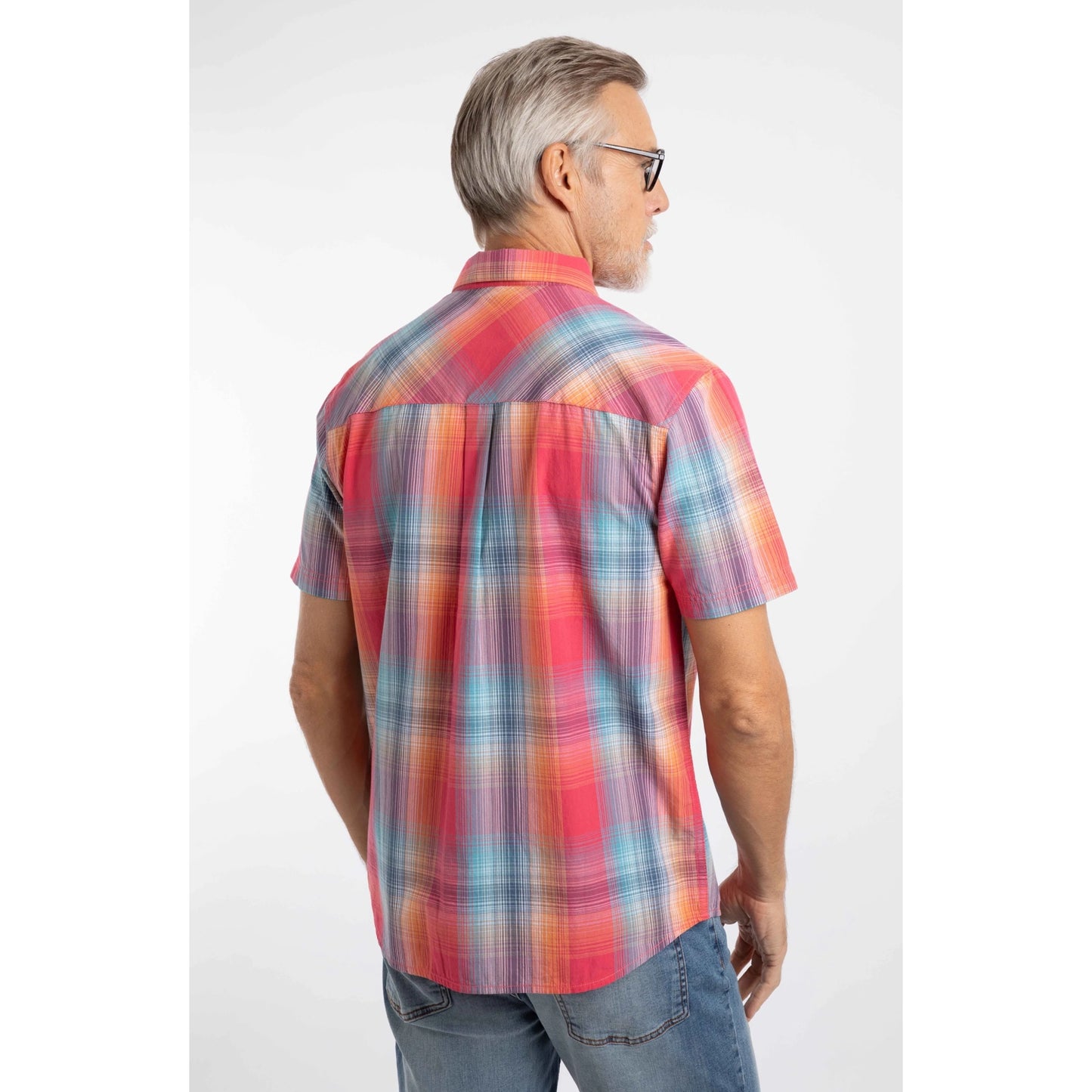 Back view of a man wearing a Weird Fish short sleeve Judd shirt in a bright Flamingo Pink, blue and orange check pattern with blue jeans.