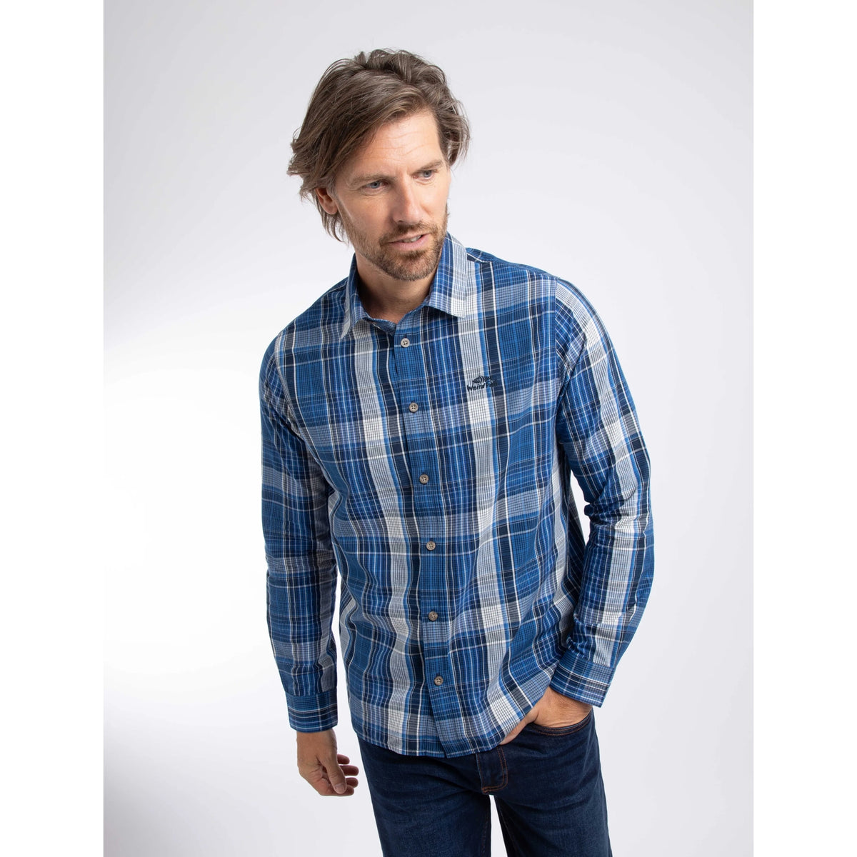 Front view of a man wearing a Weird Fish long sleeve Lando shirt, in a navy, blue and white check pattern.