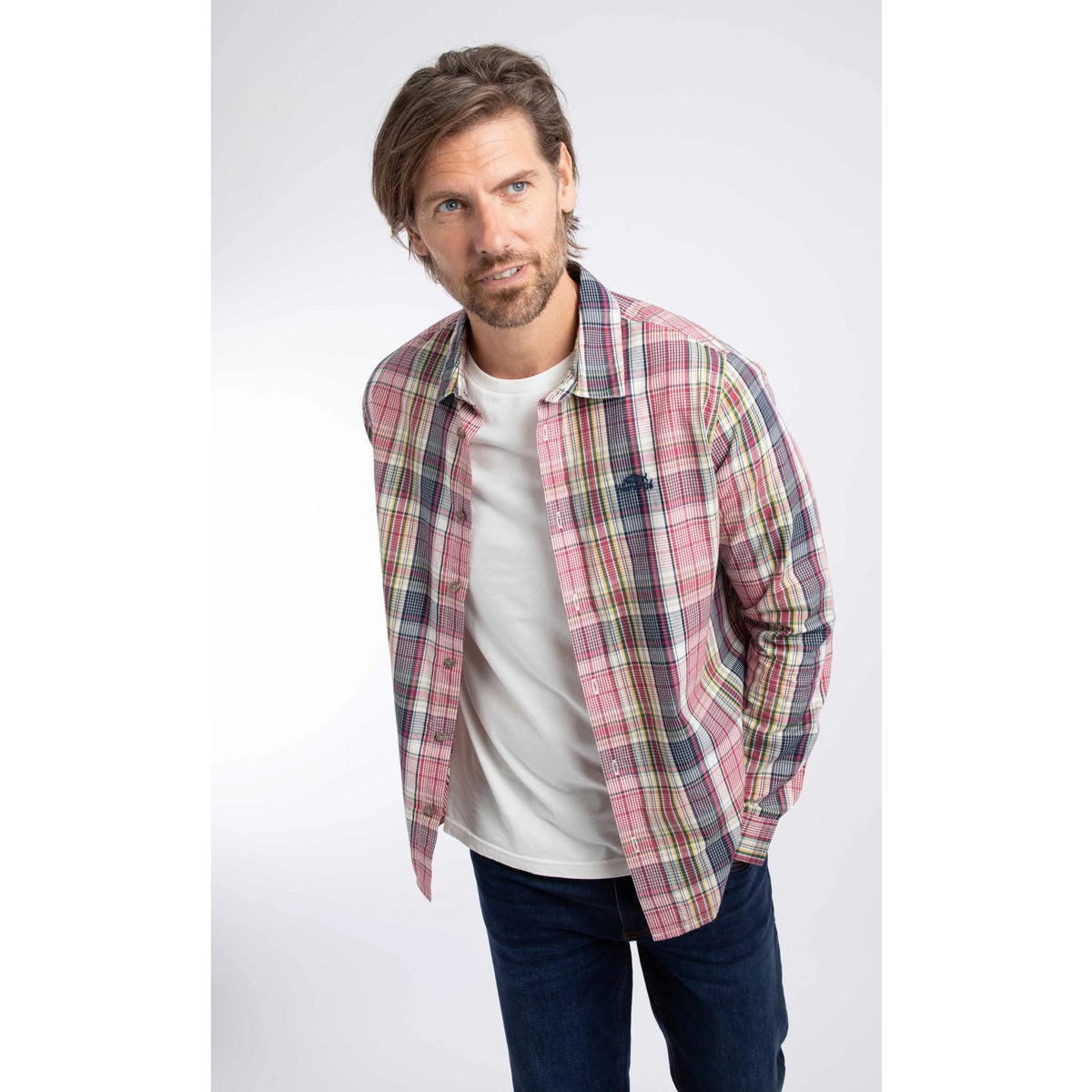 A man wearing a Weird Fish long sleeve Lando shirt, in a crushed berry, navy, yellow and white check pattern.