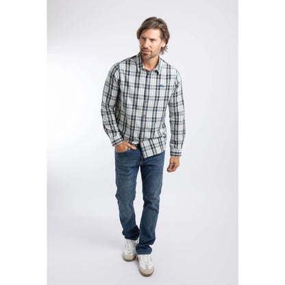 A man wearing a Weird Fish long sleeve Lando shirt, in Off White with a navy, green and orange check pattern, paired with blue jeans and white trainers.