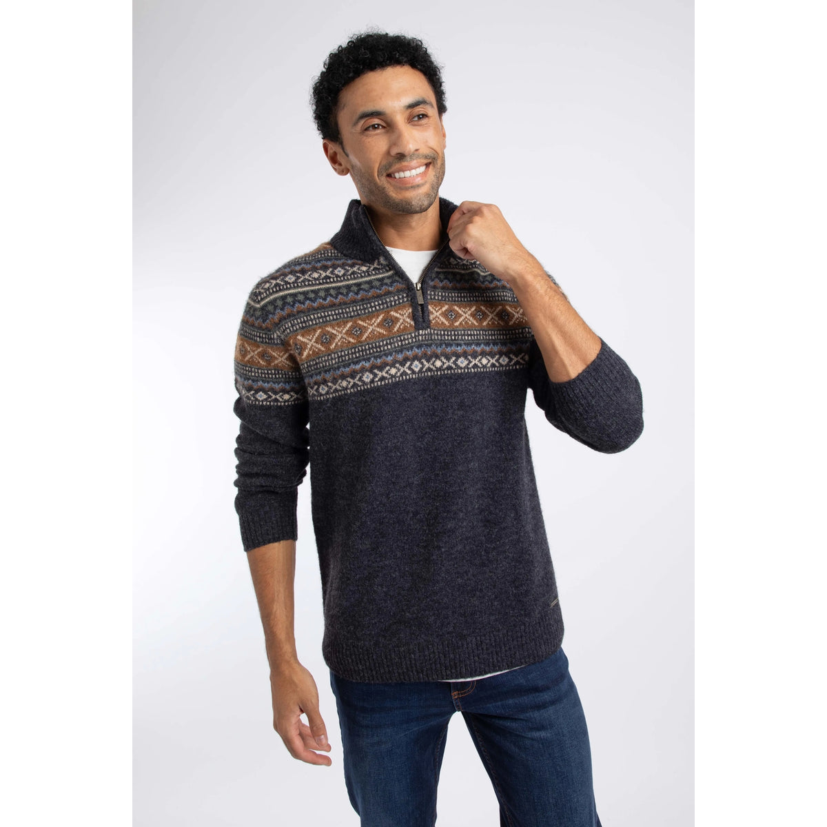 Front view of a man wearing a Weird Fish 1/4 zip Larner knitted jumper in Midnight Navy with a Fair Isle pattern across the chest and shoulders with blue jeans.