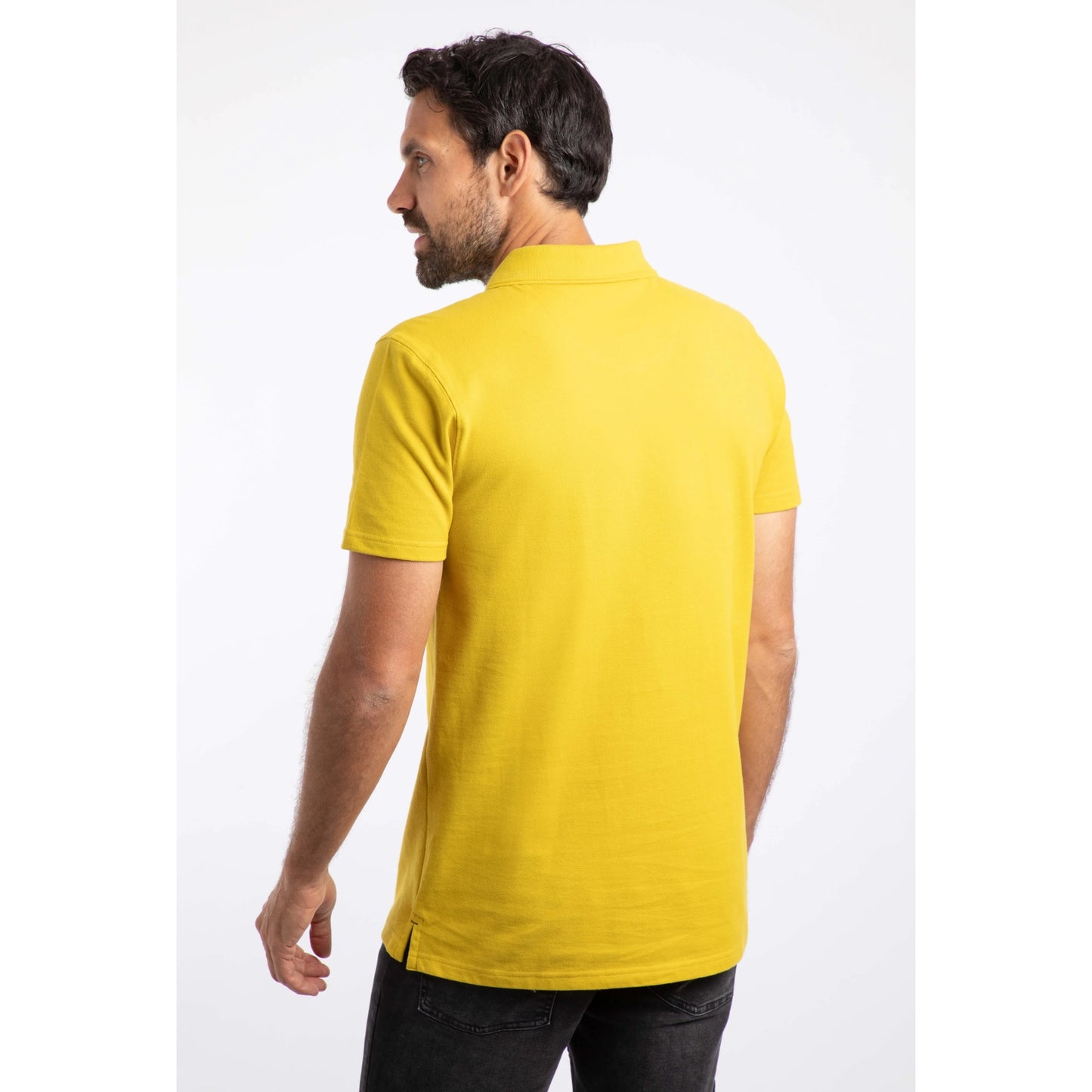 Back view of a man wearing a bright Antique Moss yellow short sleeve Weird Fish Miles polo shirt on a white background