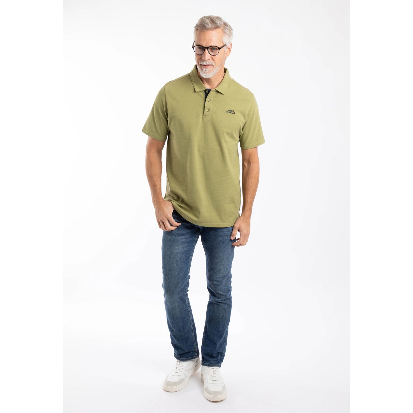 A man wearing a Weird Fish short sleeve Miles polo shirt in Washed Oak Green with blue jeans.