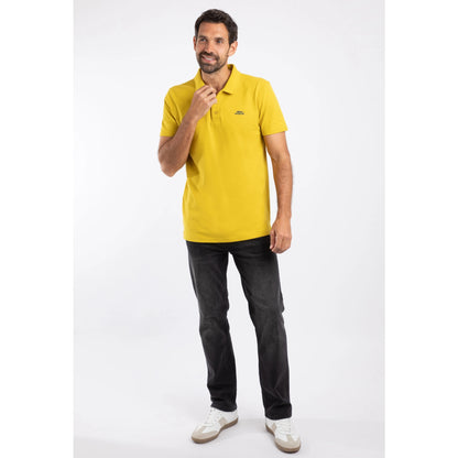 Man wearing a yellow Weird Fish Miles polo shirt and black jeans on a white background