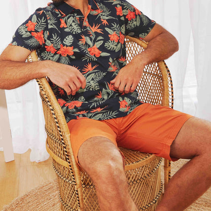 Weird Fish mens Murrisk Orange shorts worn by man sitting in wicker chair with floral shirt