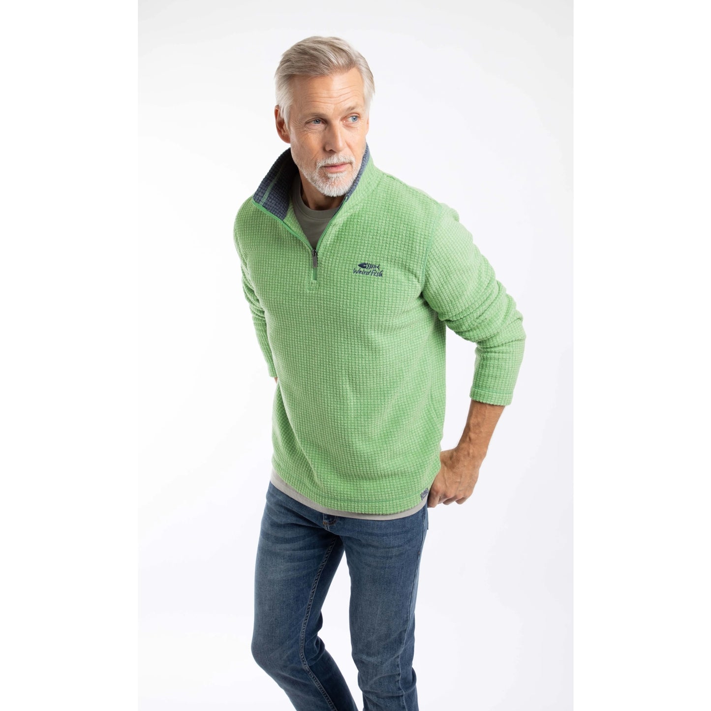 Man wearing a Weird Fish Newark 1/4 zip grid fleece in grass green, with blue jeans