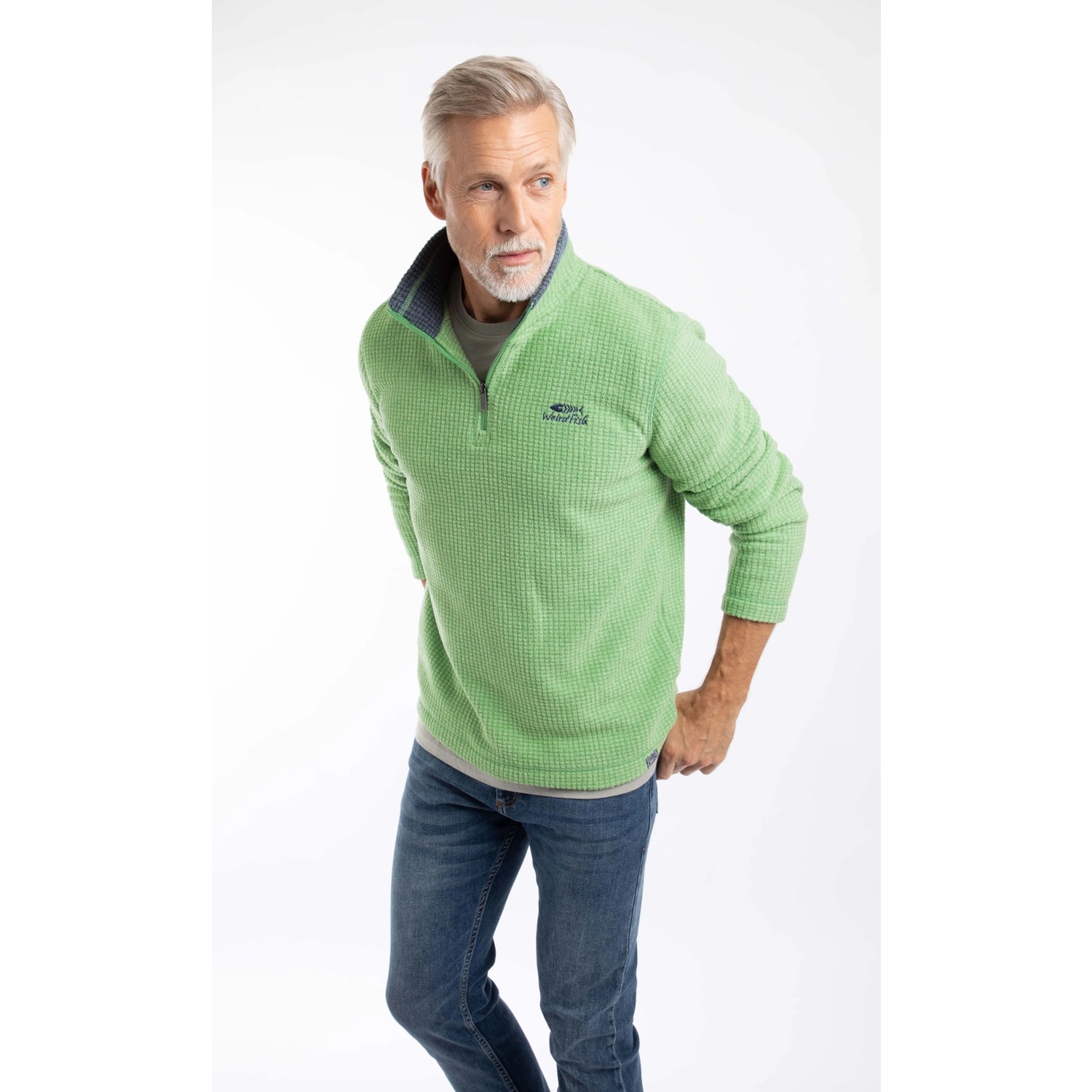 Man wearing a Weird Fish Newark 1/4 zip grid fleece in grass green, with blue jeans