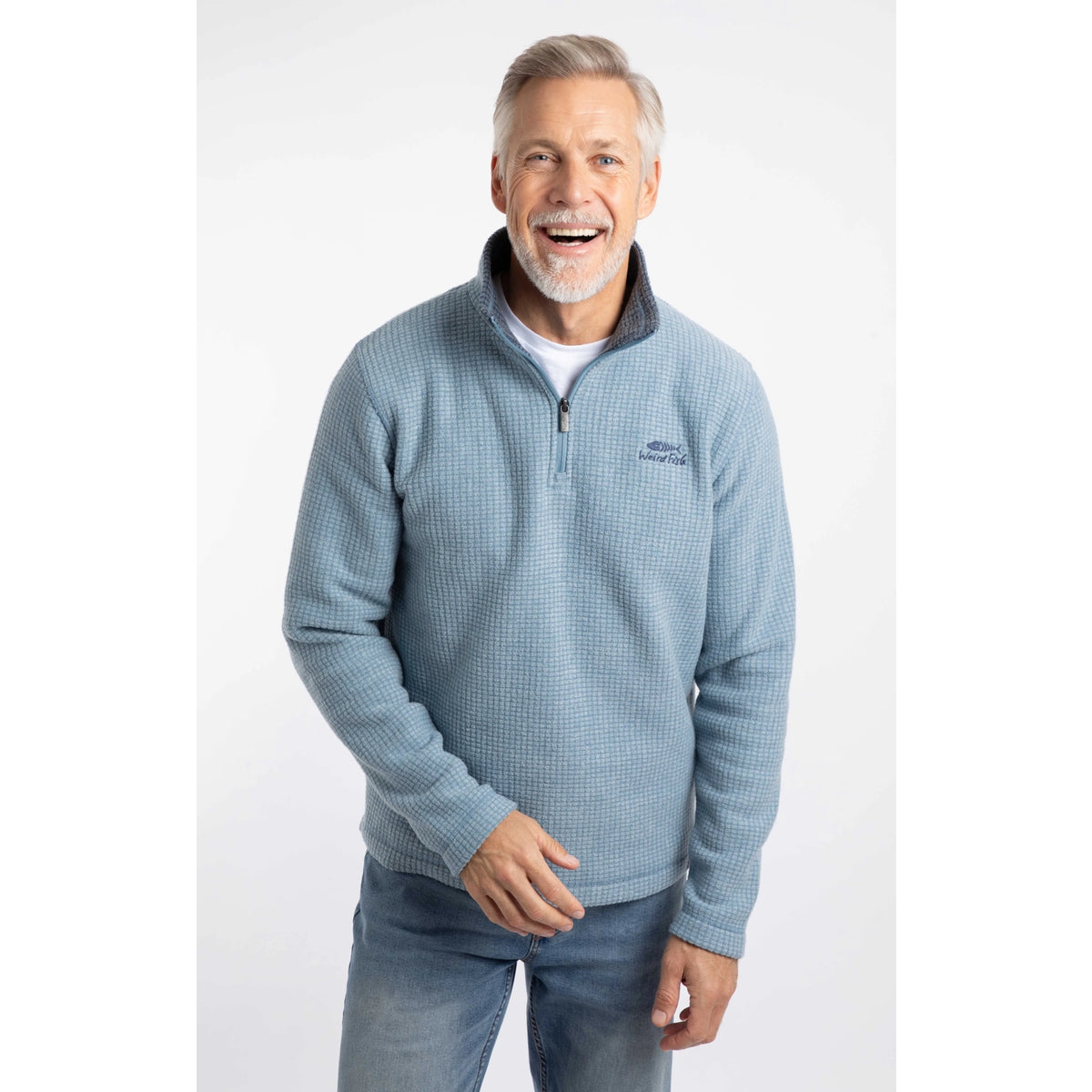Man wearing a Weird Fish Newark 1/4 zip grid fleece in light blue, with blue jeans