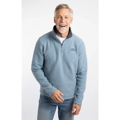 Man wearing a Weird Fish Newark 1/4 zip grid fleece in light blue, with blue jeans