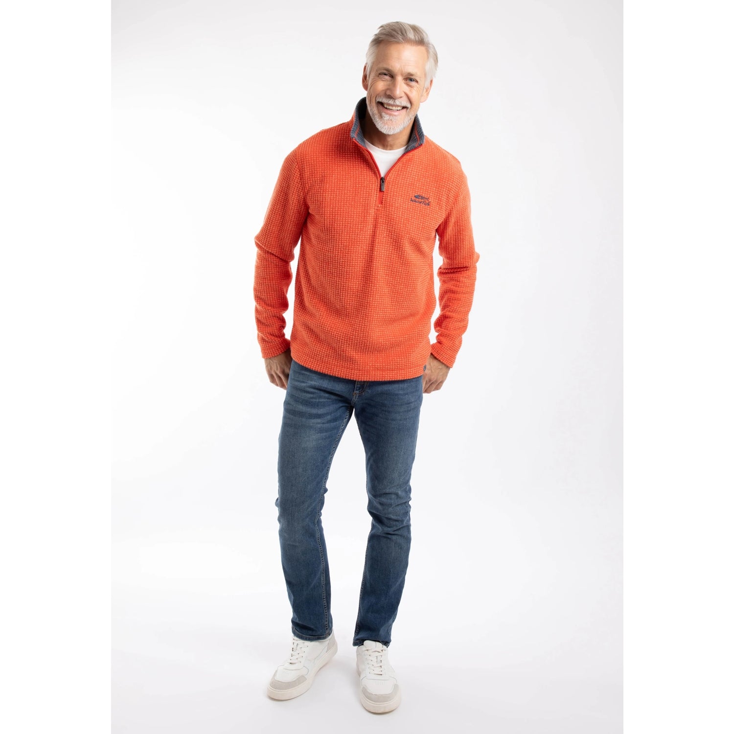 Man wearing a Weird Fish Newark 1/4 zip grid fleece in Orange Spice, with blue jeans and trainers