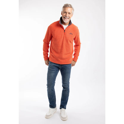 Man wearing a Weird Fish Newark 1/4 zip grid fleece in Orange Spice, with blue jeans and trainers