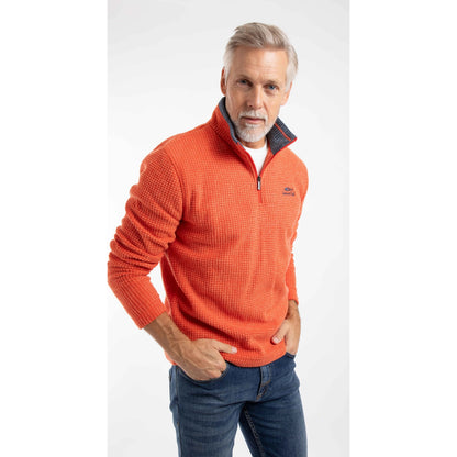 Man wearing a Weird Fish Newark 1/4 zip grid fleece in Orange Spice, with blue jeans