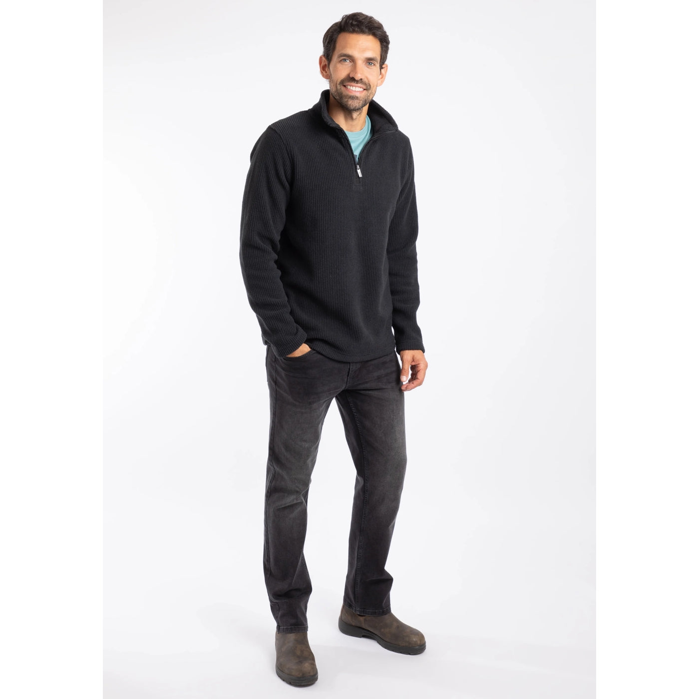 Man wearing a black Weird Fish pullover fleece and dark jeans on a white background
