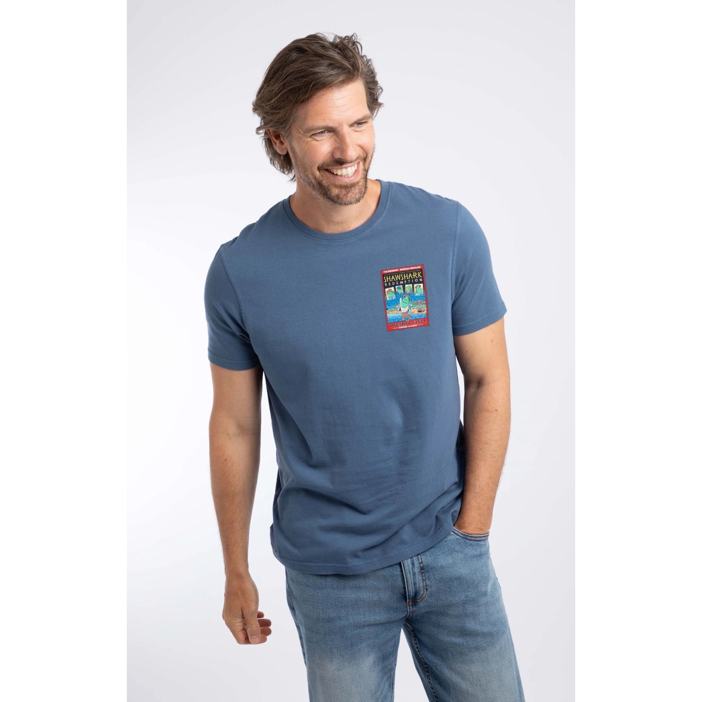 Front view of a man wearing a short sleeve t-shirt in Ensign Blue, featuring a small Shawshark Redemption parody print of The Shawshank Redemption film poster on one side of the chest.