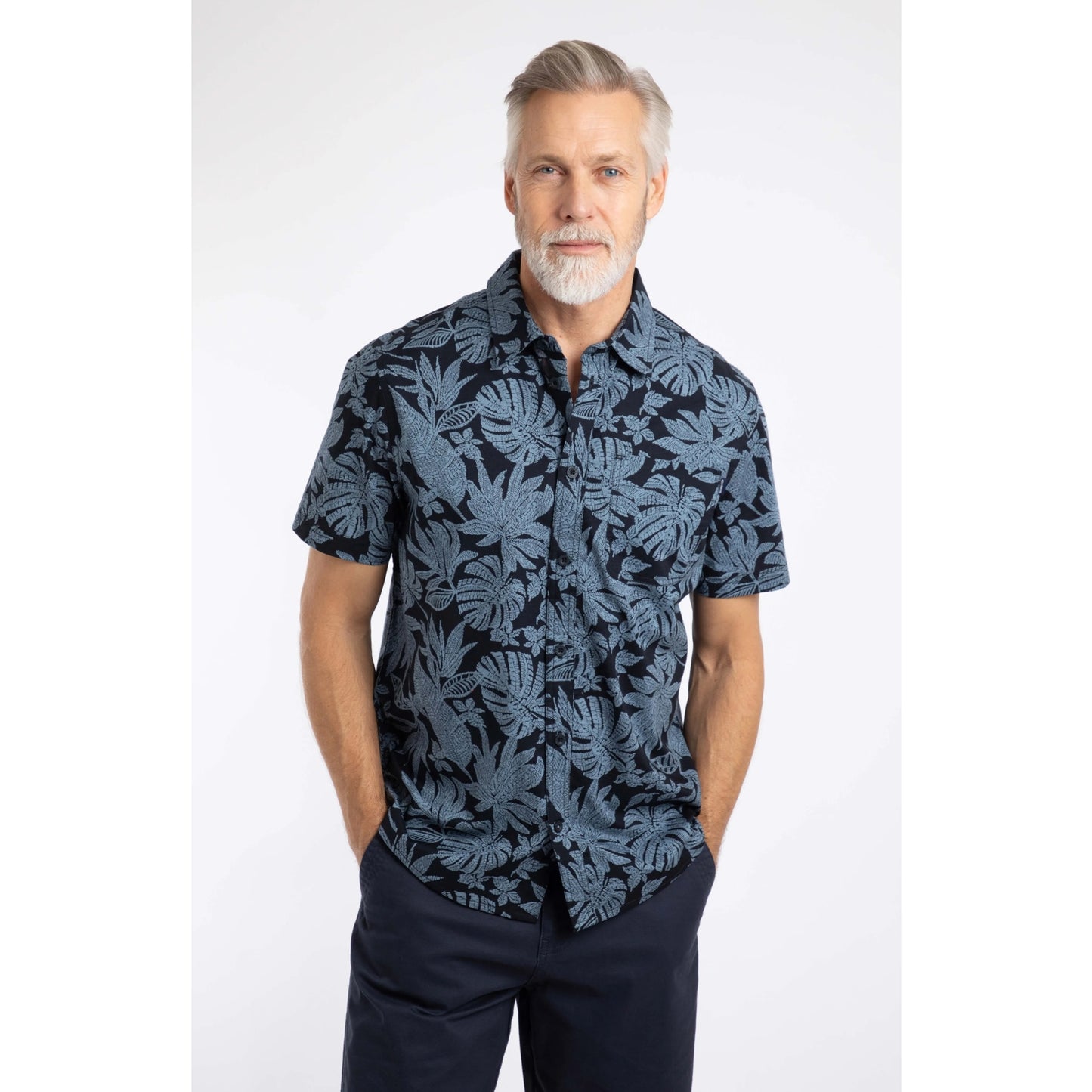 Man wearing a Weird Fish short sleeve Faraway shirt in Blue Mirage with a tropical leaf pattern