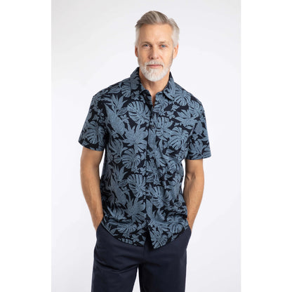 Man wearing a Weird Fish short sleeve Faraway shirt in Blue Mirage with a tropical leaf pattern