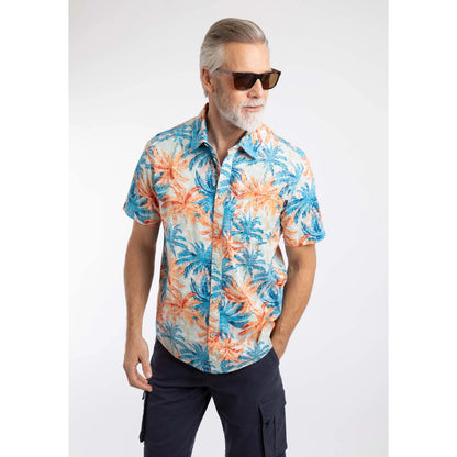 Man wearing a Weird Fish short sleeve Faraway shirt in Paprika orange and blue with a tropical palm tree pattern and navy shorts