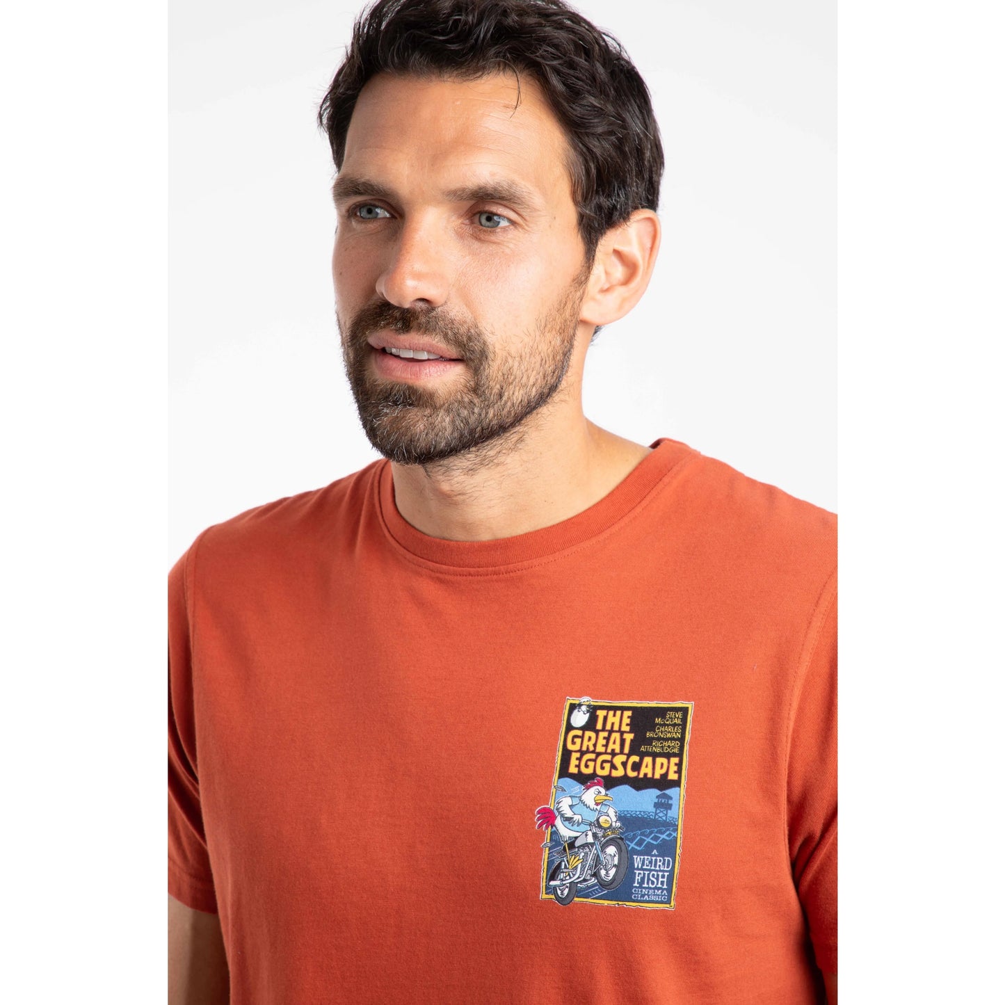 Man wearing an orange t-shirt with a graphic design on a white background