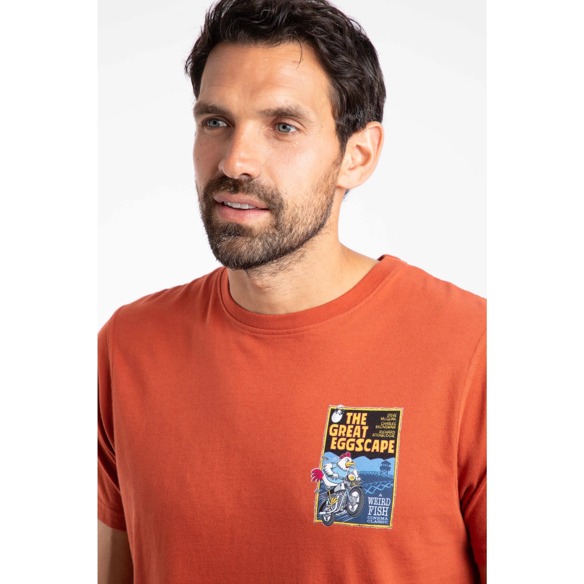 Man wearing an orange t-shirt with a graphic design on a white background