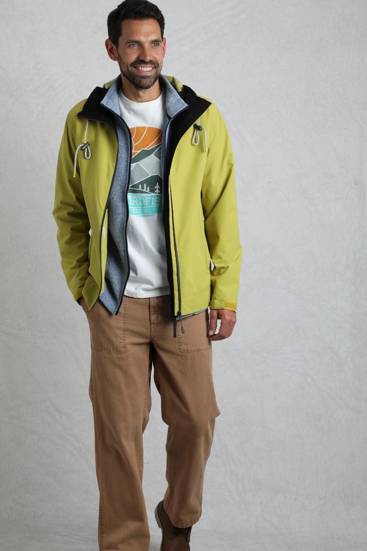 Weird Fish mens waterproof jacket tarragon in light green worn by man with casual outfit
