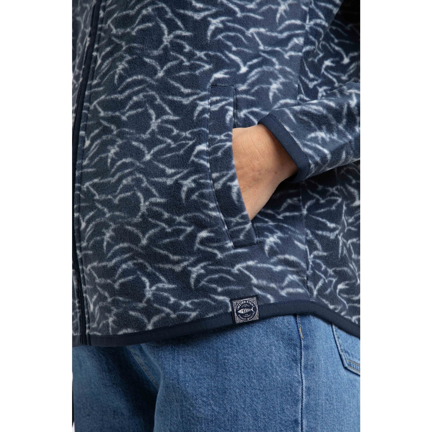 Close-up view of the tummy pocket of a womens Weird Fish full zip Rochelle microfleece in Night Blue with a gull bird print.