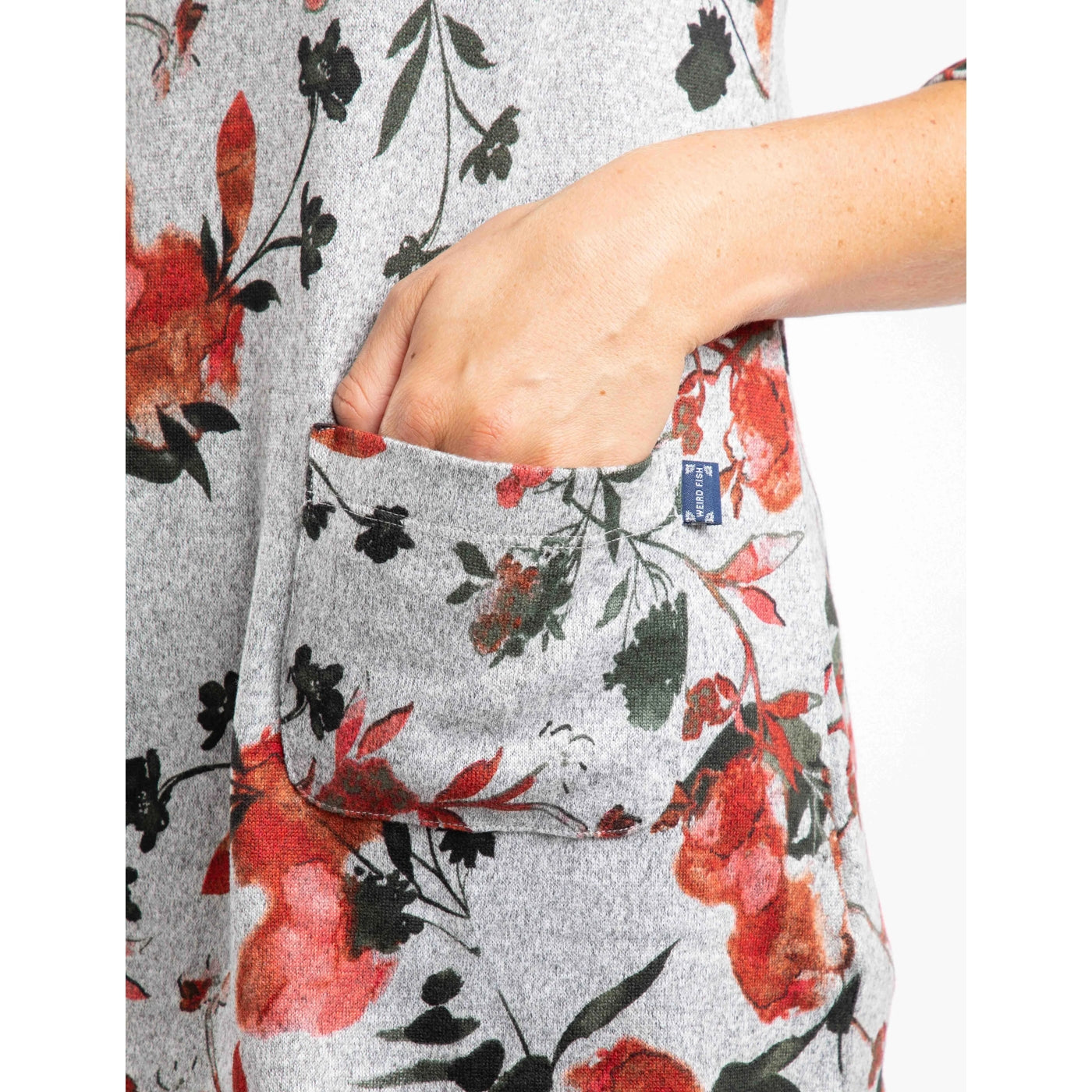 Close up of the front pocket of a Weird Fish womens floral-patterned grey Sidney tunic with a red and green floral pattern.