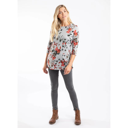 Woman wearing a grey and red floral print Weird Fish Sidney tunic with grey trousers on a white background